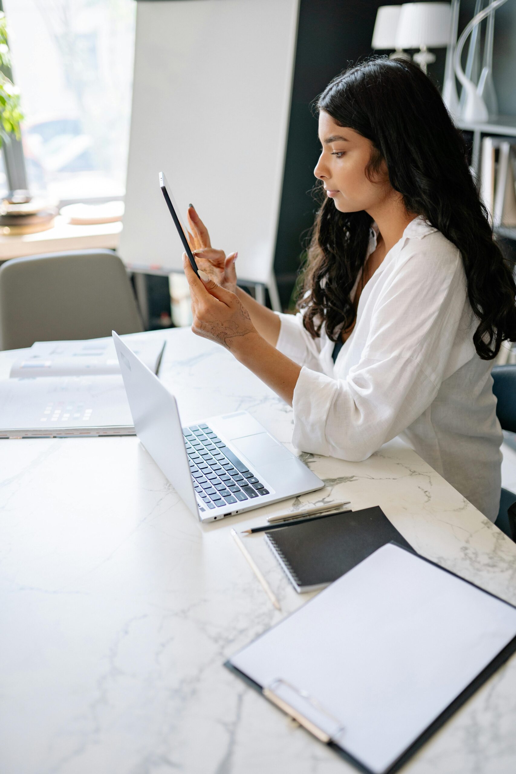 A businesswoman using a tablet in a modern office workspace.